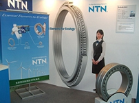 Photo: A main shaft bearing on display (right) and a panel showing a life-size illustration of an extra-large double-row tapered roller bearing