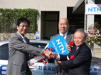 Photo: Chairman Suzuki (right) and Chairman Tajima of Tajima Motor Corporation (center) handing Mayor Watanabe the keys